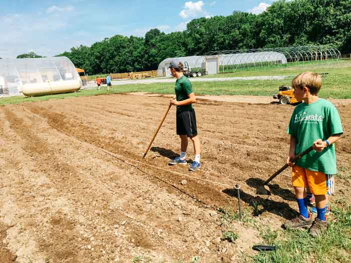 Volunteers help to till the soil for planting