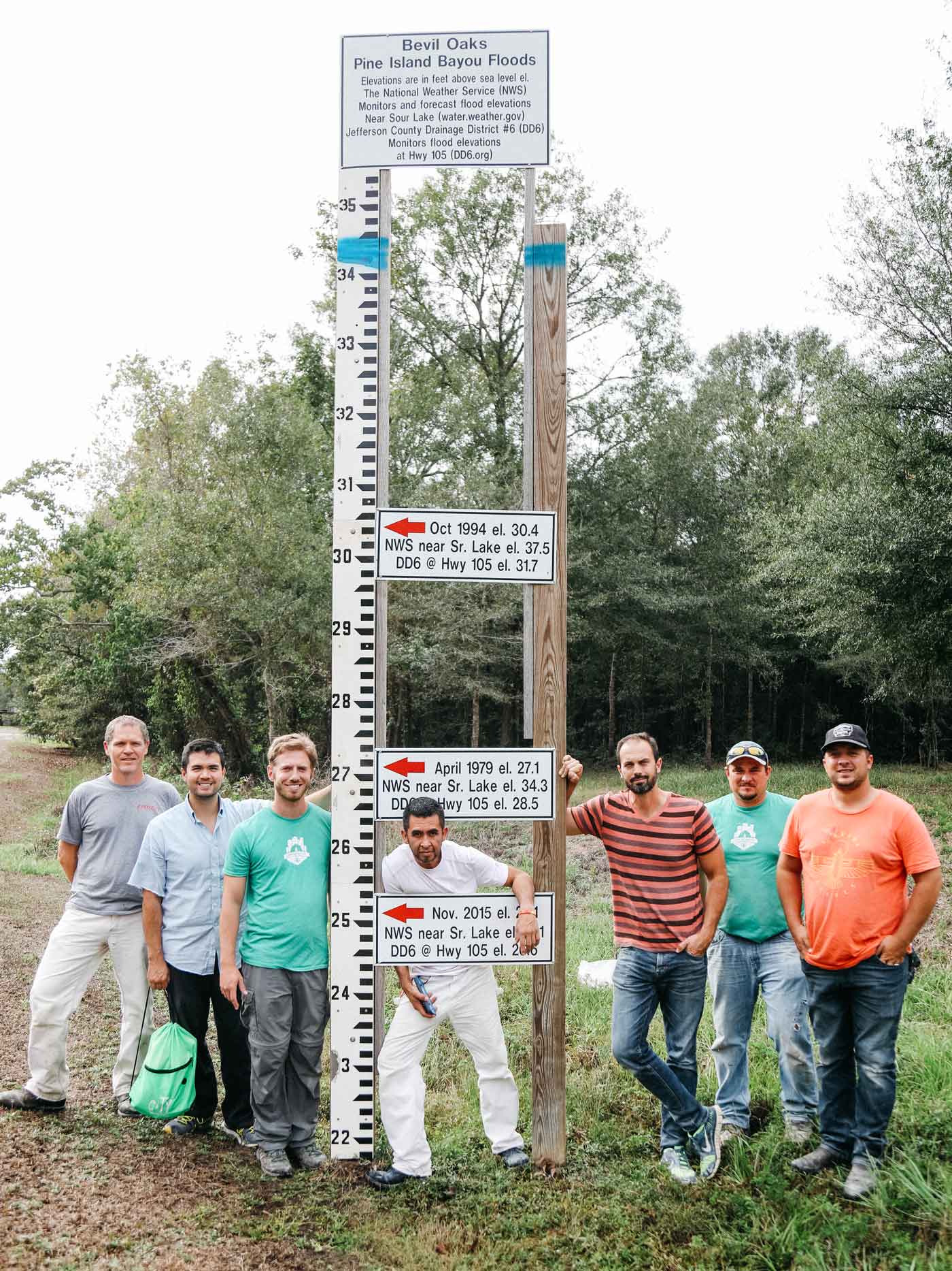 The team standing next to a flood meter in the area.&nbsp; The blue line was the water level from Harvey.